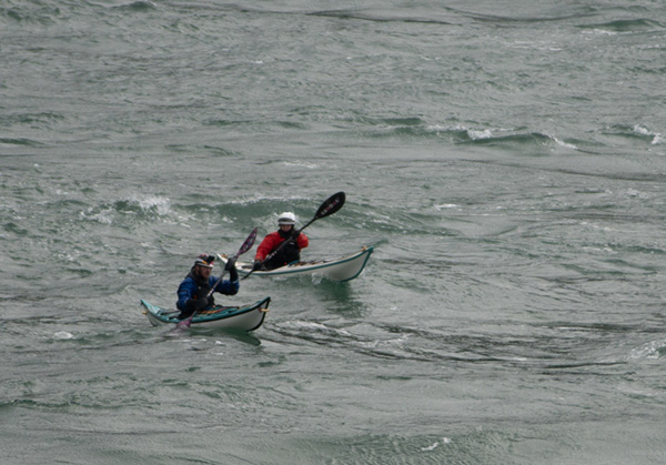 Kayakers paddling through large waves