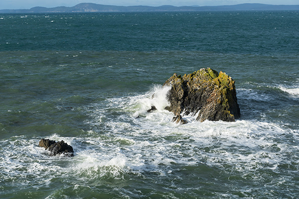 Waves crashing into a rock in the water