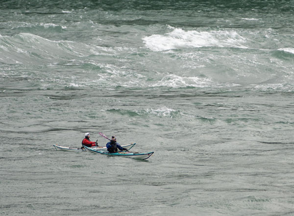 Kayakers paddling through large waves